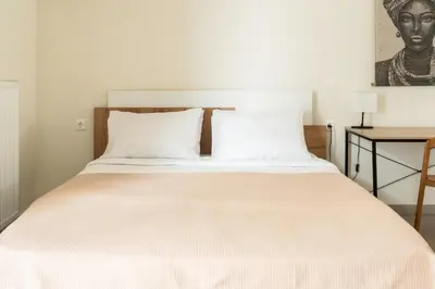 a bedroom with a bed with white sheets and a desk at Elysee apartment 8 in Athens