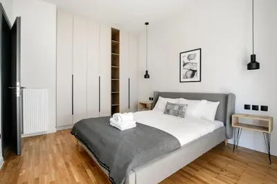 a bedroom with a large white bed and a wooden floor at Astoria - Luxury 2-BR Apartment in Athens in Athens