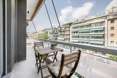 a balcony with a table and chairs and a building at Astoria - Luxury 2-BR Apartment in Athens in Athens
