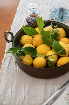 a basket of lemons with leaves on top of a table at Florou's art-gallery apartment, Kypseli in Athens