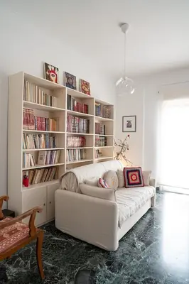 a white couch in a living room with bookshelves at Florou's art-gallery apartment, Kypseli in Athens