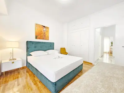a white bedroom with a large bed with a blue headboard at Athens Belvedere Palace in Athens