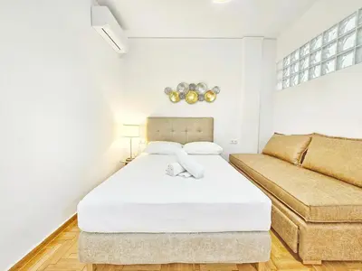 a white bedroom with a bed and a couch at Athens Belvedere Palace in Athens