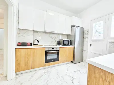 a white kitchen with wooden cabinets and a refrigerator at Athens Belvedere Palace in Athens