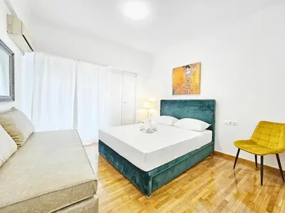 a white bedroom with a bed and a chair at Athens Belvedere Palace in Athens