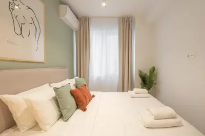 a bedroom with a white bed with pillows and a window at Praxitelous Hideout in Athens