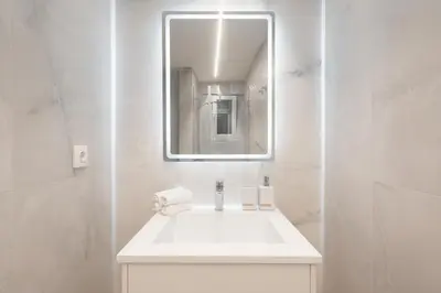 a white bathroom with a sink and a mirror at Praxitelous Hideout in Athens