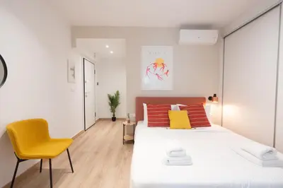 a white bedroom with a bed and a yellow chair at Praxitelous Hideout in Athens