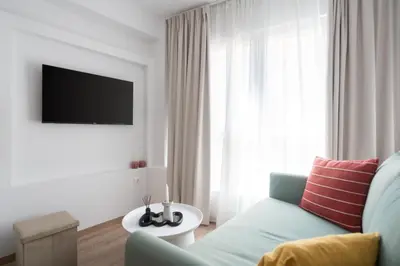a living room with a blue couch and a tv at Praxitelous Hideout in Athens