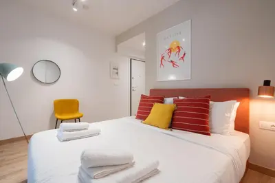 a bedroom with a white bed with red and yellow pillows at Praxitelous Hideout in Athens