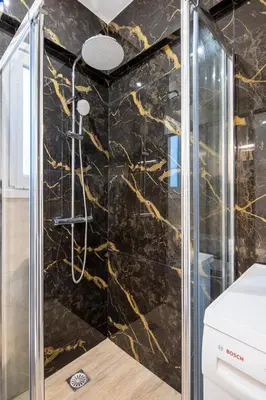 a shower in a bathroom with a black marble wall at Artistic Stay in the Heart of Athens in Athens