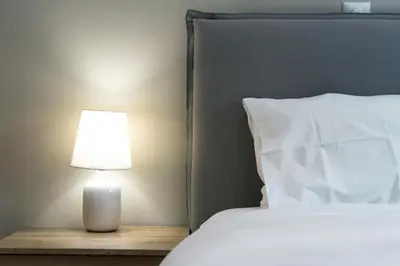 a bed with a lamp on a table next to it at Amazing house close to sea in Athens