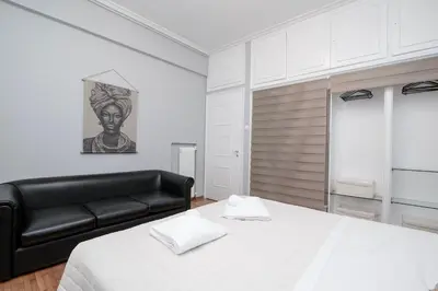 a bedroom with a bed and a black leather couch at FilOikos Syntagma Spacious Suite 5Br 2,5Ba in Athens