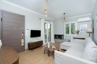 a living room with a white couch and a tv at Villa Hyacinth by A&D Properties in Porto Rafti