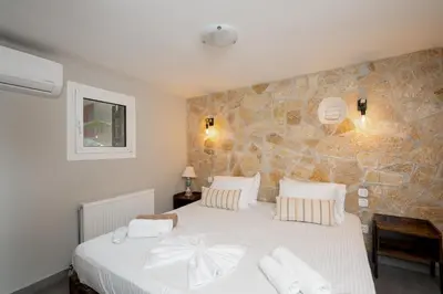 a bedroom with a large white bed with a stone wall at Villa Hyacinth by A&D Properties in Porto Rafti