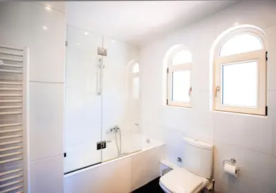 a white bathroom with a toilet and a bath tub at South Blue Tranquil Villa in Athens