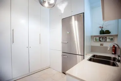a kitchen with white cabinets and a stainless steel refrigerator at South Blue Tranquil Villa in Athens