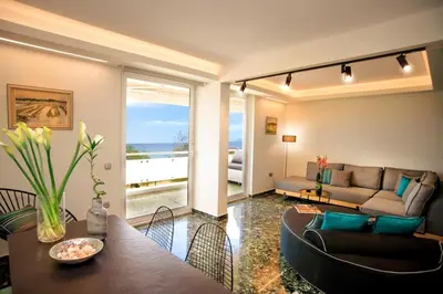 a living room with a couch and a table at Vouliagmeni Kavouri Beachfront Apartment in Athens