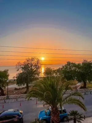 a sunset over a parking lot with a palm tree at Vouliagmeni Kavouri Beachfront Apartment in Athens
