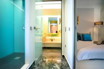 a bedroom with a bed and a bathroom with a mirror at Vouliagmeni Kavouri Beachfront Apartment in Athens
