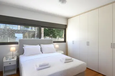 a bedroom with a white bed and a window at Saronida Seaside Serenity in Saronida