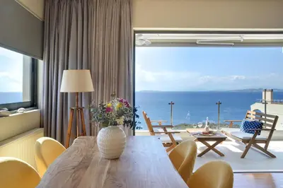 a dining room with a table and a view of the ocean at Saronida Seaside Serenity in Saronida