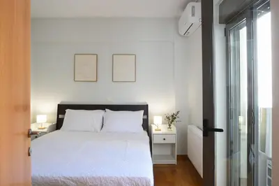 a bedroom with a white bed and a window at Saronida Seaside Serenity in Saronida