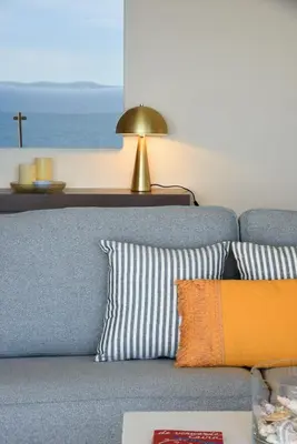 a blue couch with pillows and a table with a lamp at Saronida Seaside Serenity in Saronida