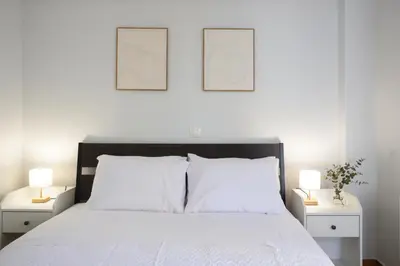 a bedroom with a white bed with two pictures on the wall at Saronida Seaside Serenity in Saronida
