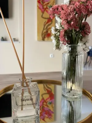 a glass vase with flowers sitting on a table at Skyway Comfort Residences in Spáta