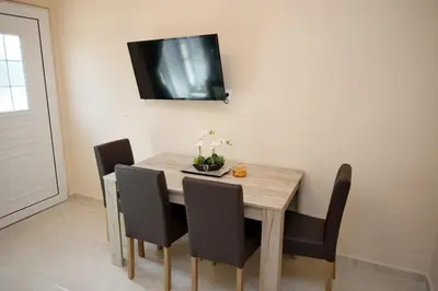 a dining room table with chairs and a television on the wall at Skyway Comfort Residences in Spáta