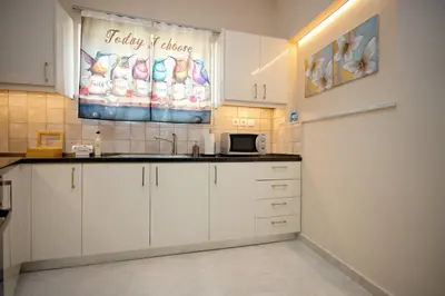 a kitchen with white cabinets and a sign on the wall at Skyway Comfort Residences in Spáta