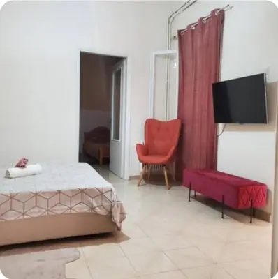 a bedroom with a bed and a chair and a tv at Home away from home - 3BR - 14' walk to port in Piraeus