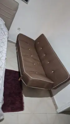 a brown bench sitting in a room with rugs at Home away from home - 3BR - 14' walk to port in Piraeus