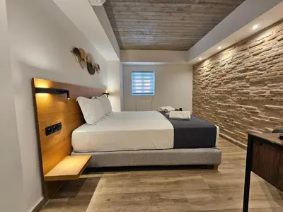a bedroom with a bed and a stone wall at Silk Suites by YHA in Athens