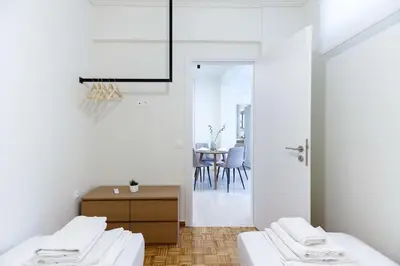 a white room with two beds and a table at Modern 2-Bedroom Apartment in Downtown Glyfada in Athens