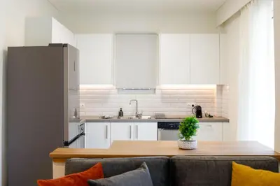 a kitchen with white cabinets and a wooden table at Modern 2-Bedroom Apartment in Downtown Glyfada in Athens
