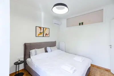 a white bedroom with a bed with white sheets at Modern 2-Bedroom Apartment in Downtown Glyfada in Athens