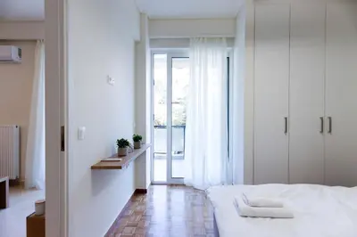 a white bedroom with a bed and a window at Modern 2-Bedroom Apartment in Downtown Glyfada in Athens