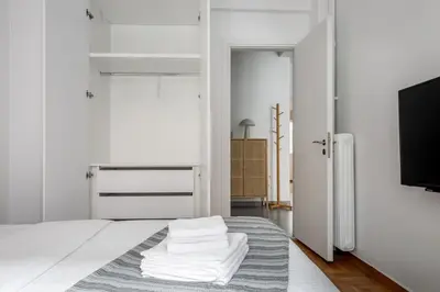 a bedroom with a bed with white sheets and a tv at Selesta - Stylish 2 Bedroom Apartment in Athens in Athens