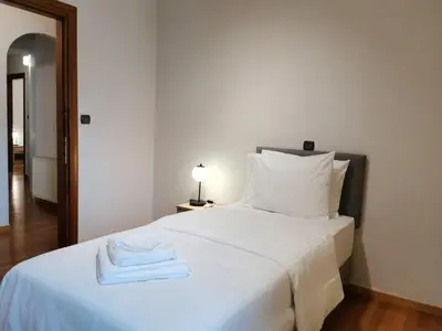a bedroom with a white bed with two towels on it at Temple of Zeus 3BD Apartment in Athens