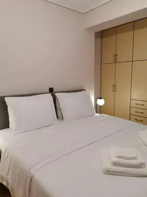 a bedroom with a white bed with white pillows at Temple of Zeus 3BD Apartment in Athens