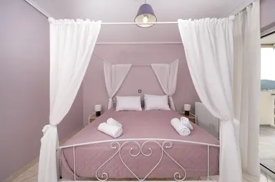 a bedroom with a pink bed with white pillows at Terminal Square Suites in Markopoulo