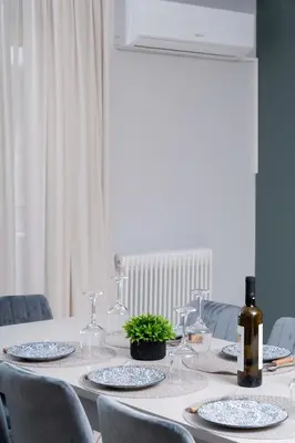 a white table with glasses and a bottle of wine at Terminal Square Suites in Markopoulo