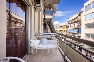 a white chair on a balcony with a pillow at Modern 2BR Apartment with Balcony Near Metro in Athens