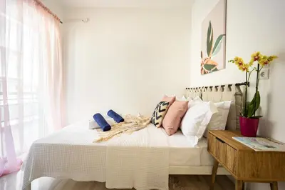 a bedroom with a white bed with pillows and a window at Modern 2BR Apartment with Balcony Near Metro in Athens