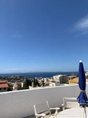 a view of the ocean from a balcony with chairs and an umbrella at Blue Echoes in Saronida