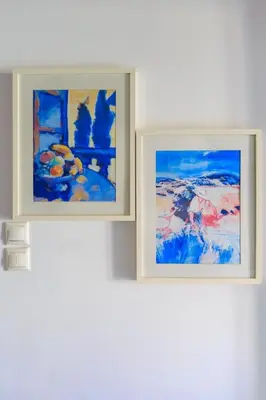 two paintings hanging on a white wall at AIOLOS Glyfada LUX Escape suite 6 in Athens