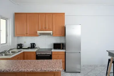 a kitchen with wooden cabinets and a white refrigerator at The Sunrise Apartment By Athens Airport 1 in Spáta