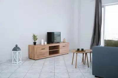 a living room with a tv on a wooden dresser at The Sunrise Apartment By Athens Airport 1 in Spáta